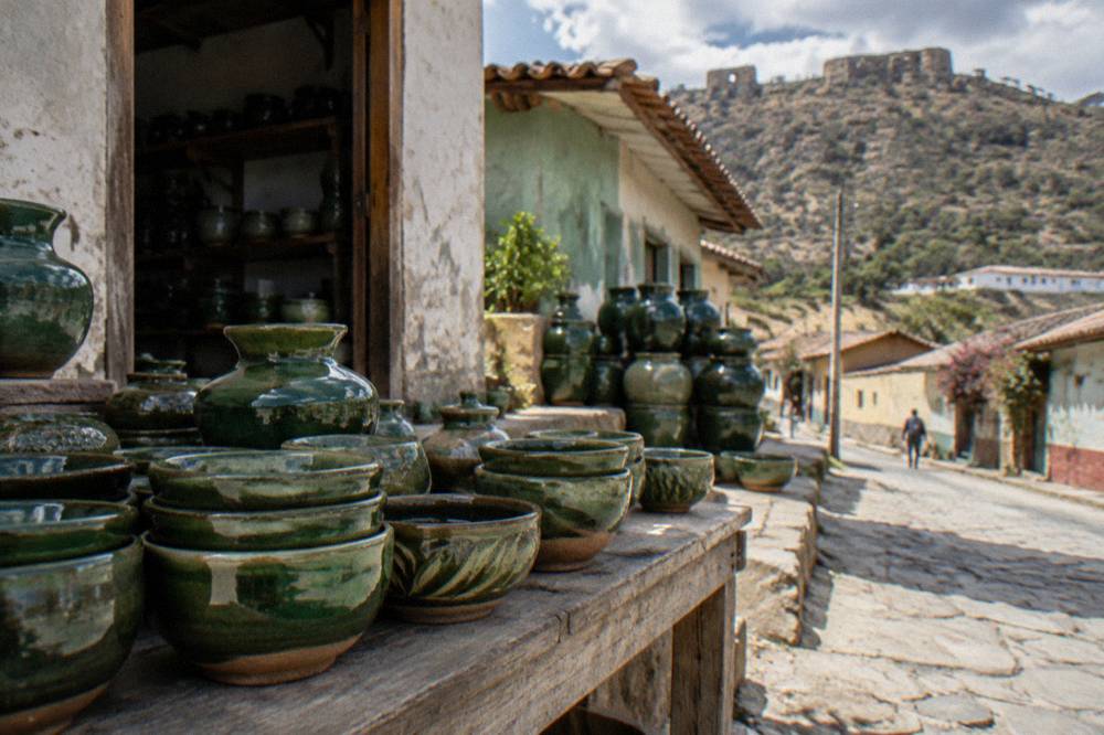 Glazed ceramic bowls and pots displayed on a wooden table in a village workshop