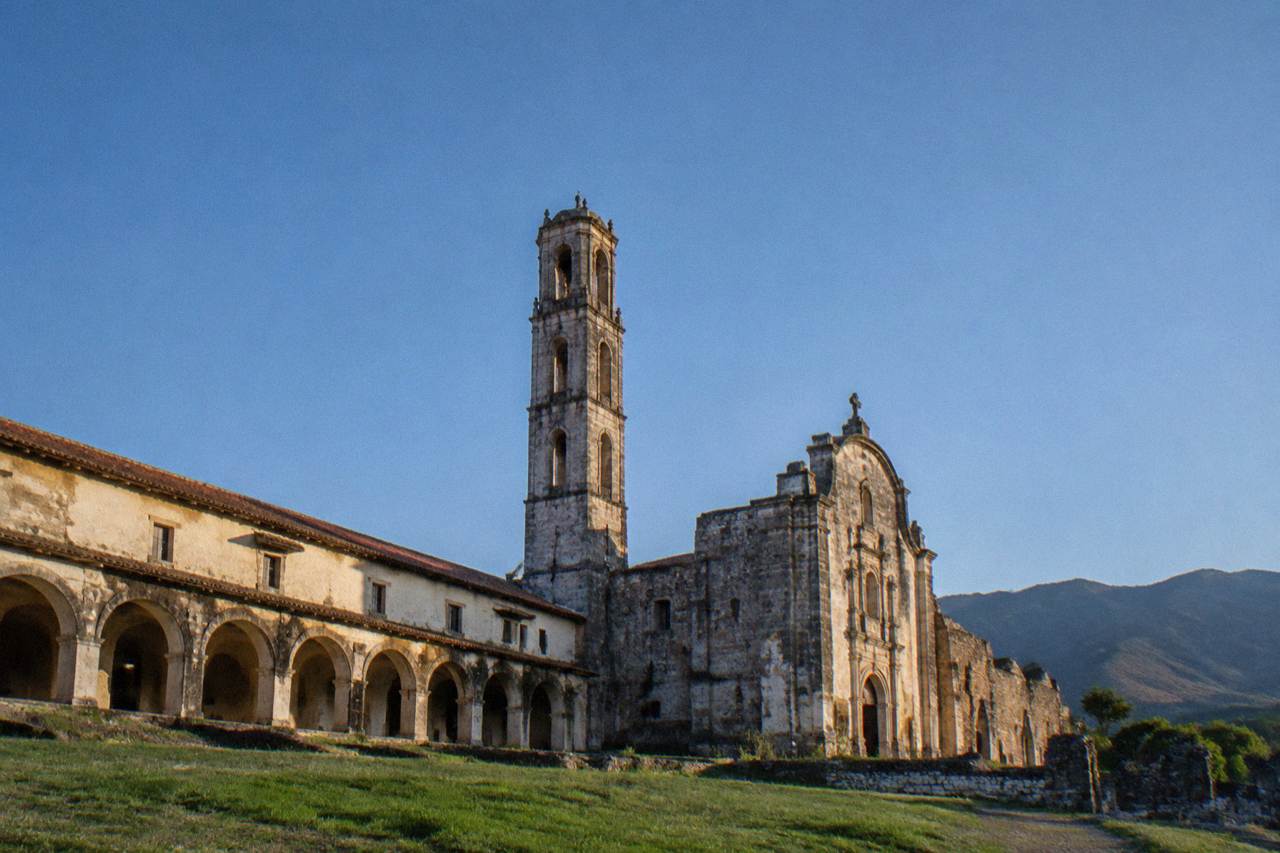 Monastery ruins with a bell tower beside a church facade under a clear sky