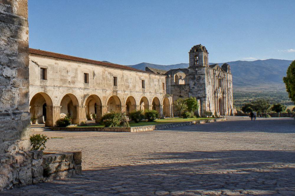 A stone facade with a weathered wall and a clear sky above a quiet square
