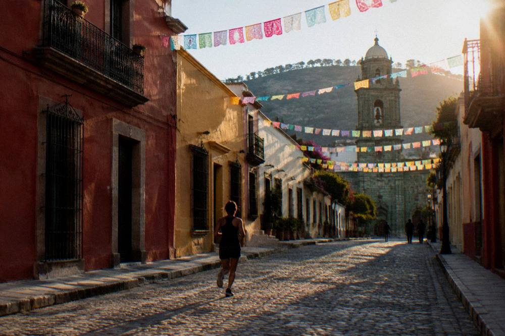 An evening street in Oaxaca City with paper flags strung overhead and warm light