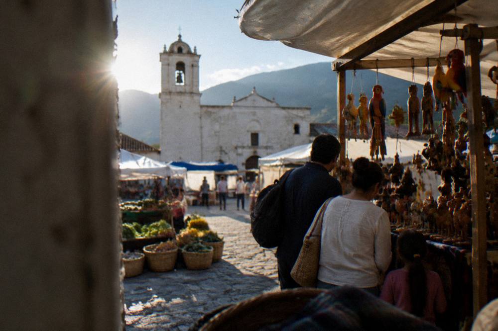A family browsing a craft stall hung with painted wooden figures