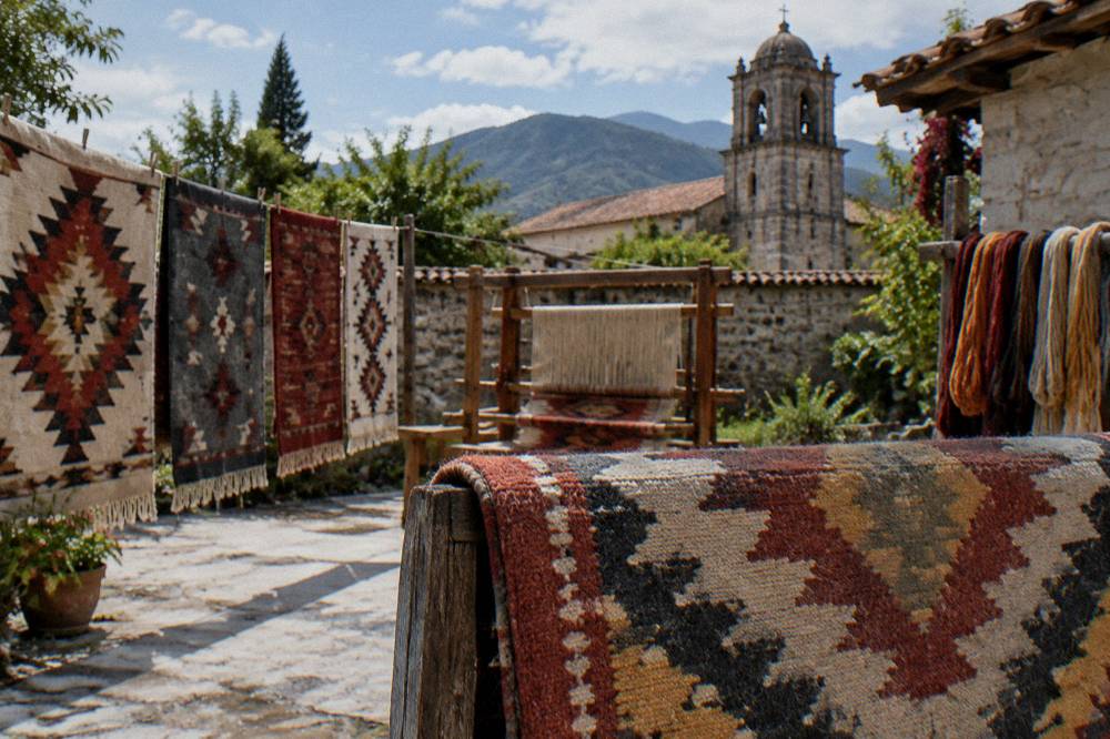 A finished rug with geometric patterns folded over a rail in daylight