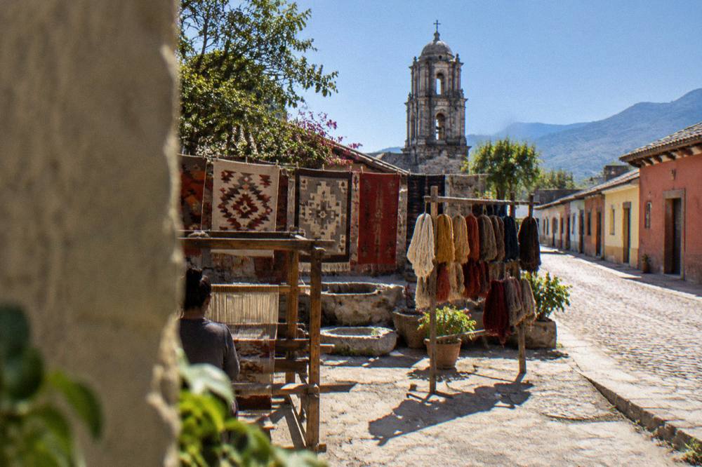 A Oaxaca valley town street with low colourful buildings under a clear sky