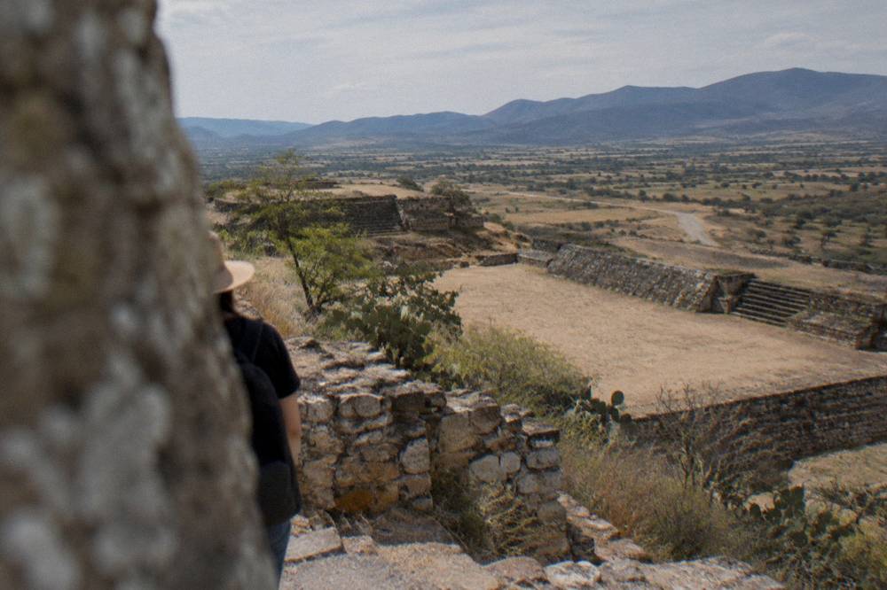 An open valley landscape with ruins, distant mountains and a gravel road in Oaxaca