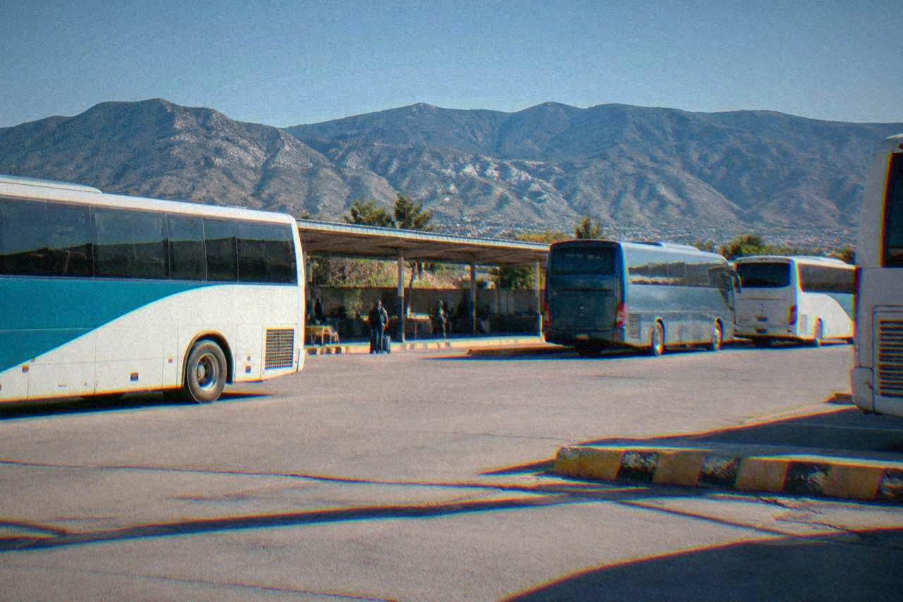 Intercity buses parked at a bus terminal in Oaxaca City with mountains behind