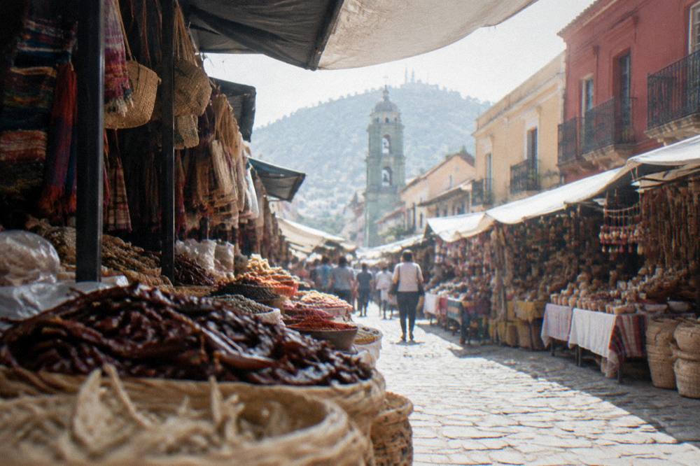 A busy covered market aisle in Oaxaca with stalls of food and crafts