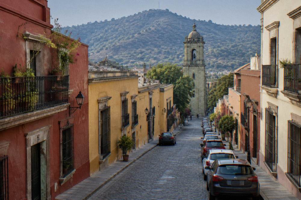 A quiet Oaxaca street in early morning with coloured walls and parked cars