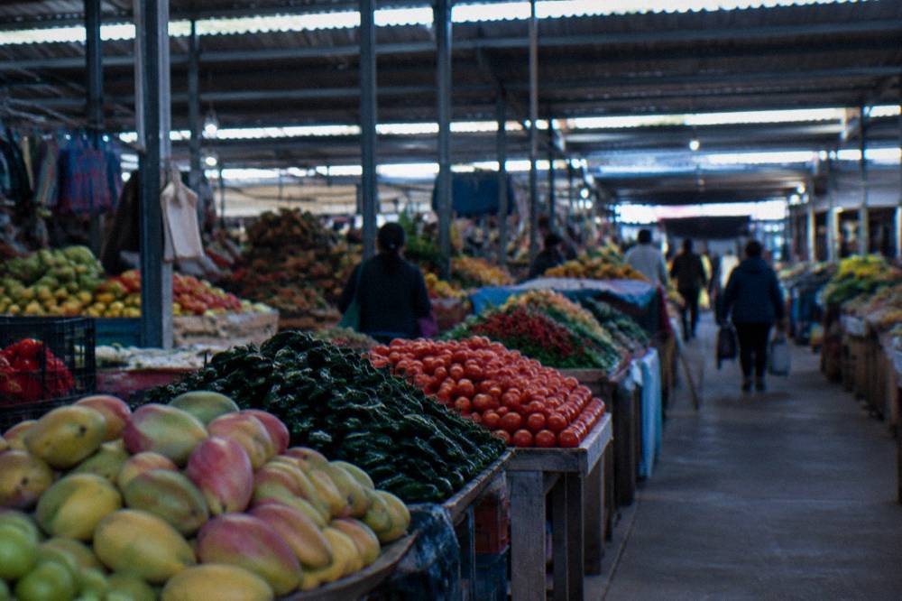 Rows of fruit and vegetable stalls under the roof of a traditional indoor market in Oaxaca