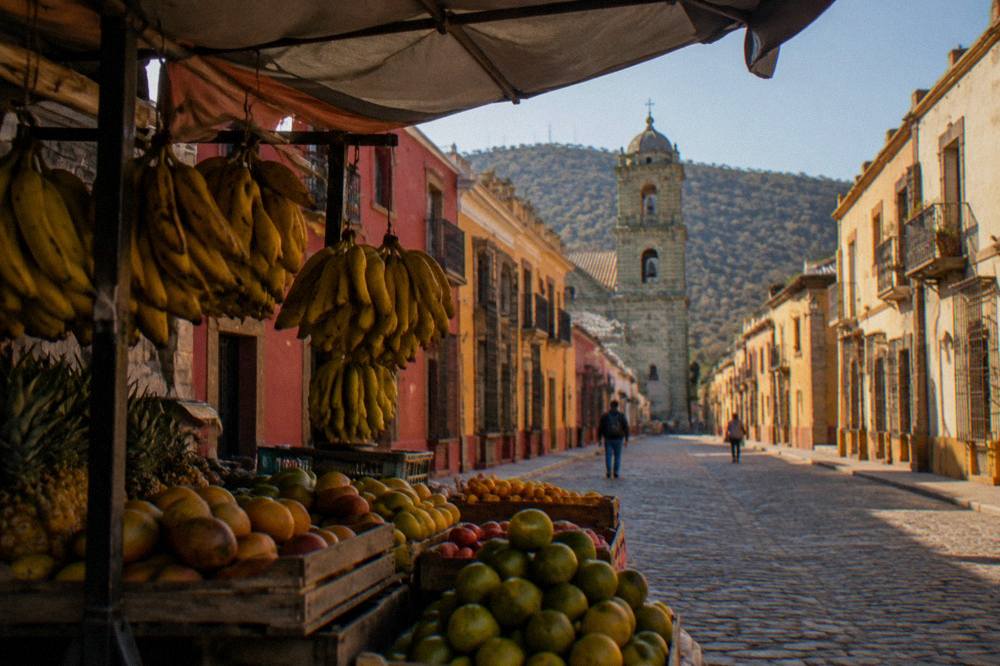A covered market stall with hanging banana bunches and crates of tropical fruit in Oaxaca