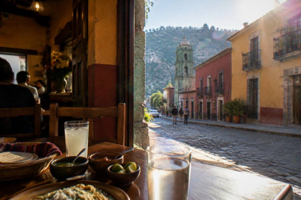 Diners seated at a small table with tortillas, salsas and drinks in a warmly lit Oaxacan restaurant