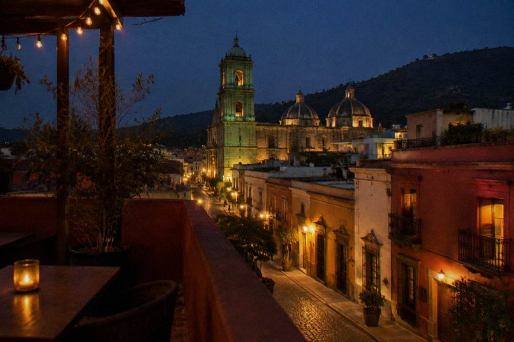 Rooftop terrace of a small Oaxaca hotel overlooking church domes at dusk