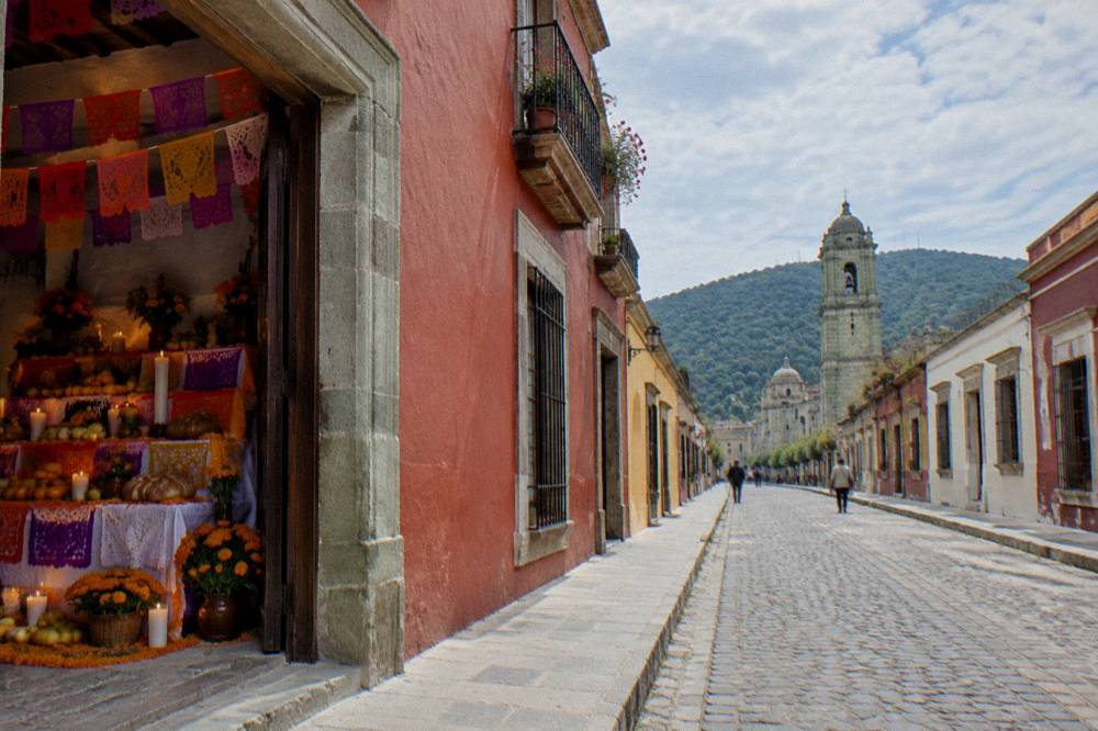 A decorated public altar with fruit, bread, candles and paper cutouts inside a Oaxaca building