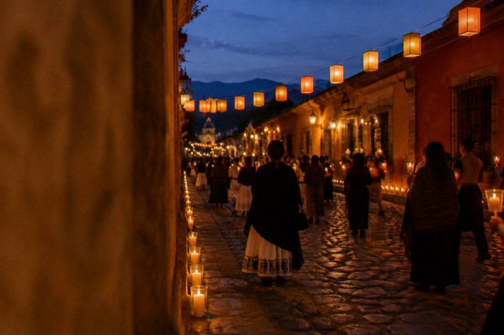 A Oaxacan street at night lit by candles and paper lanterns during a festival procession