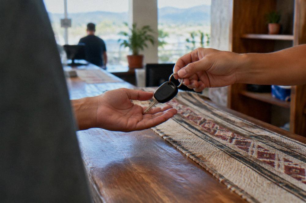 Rental car keys being handed over at a counter in a bright arrivals hall