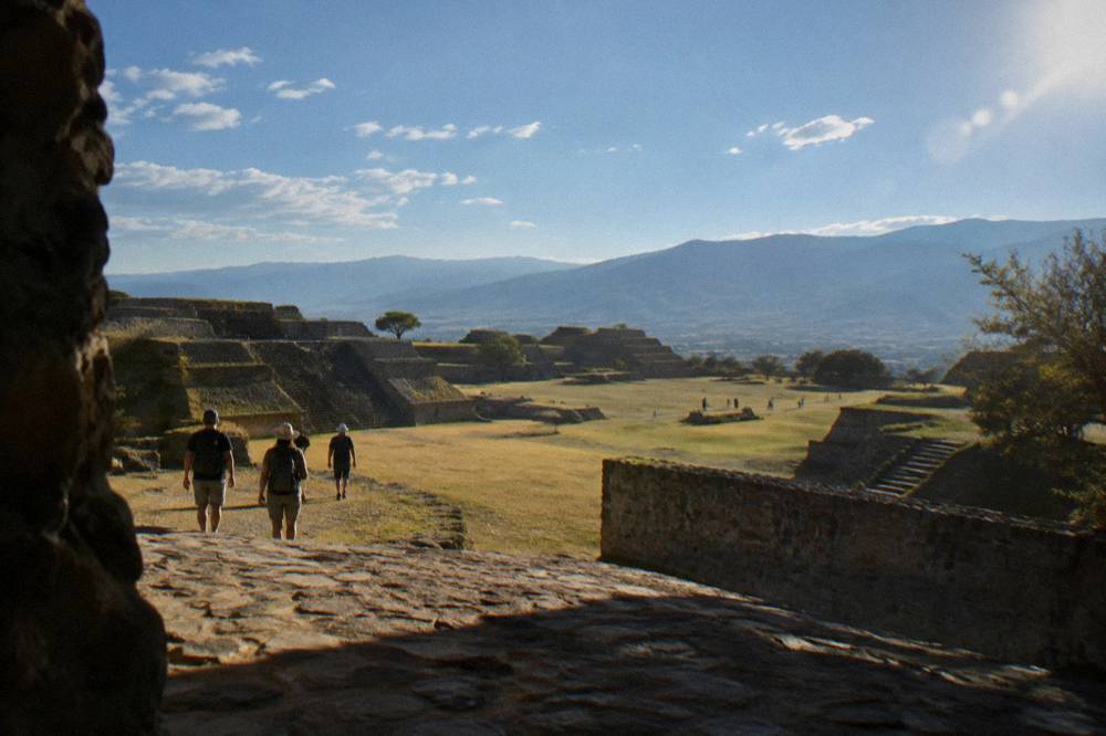 Visitors walking the terraces of Monte Albán under a wide sky