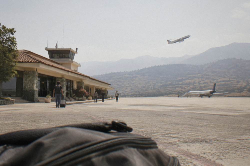 A plane climbing over a highland valley with terraced hills below