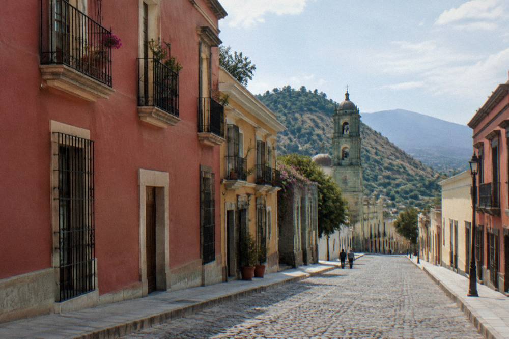 A mountain road winding through dry hills towards a distant valley in Oaxaca