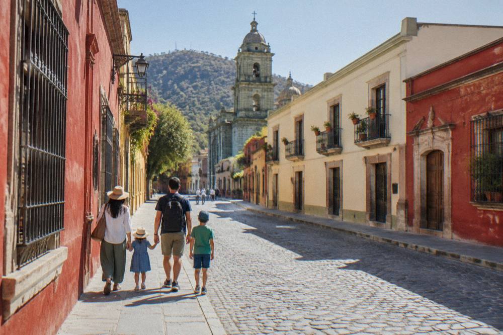 A family walking along a colourful colonial street in Oaxaca City
