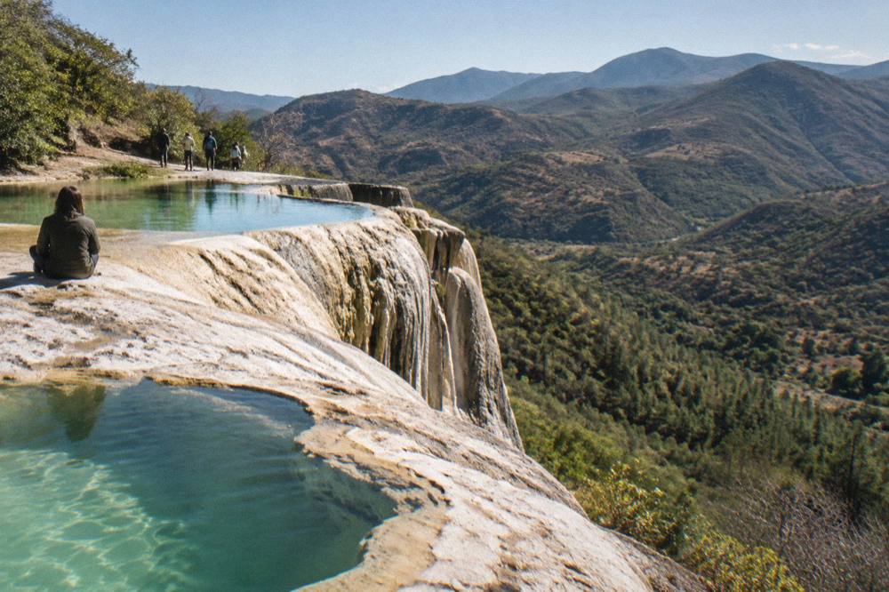 Mineral terraces of a petrified waterfall above green pools in a mountain valley