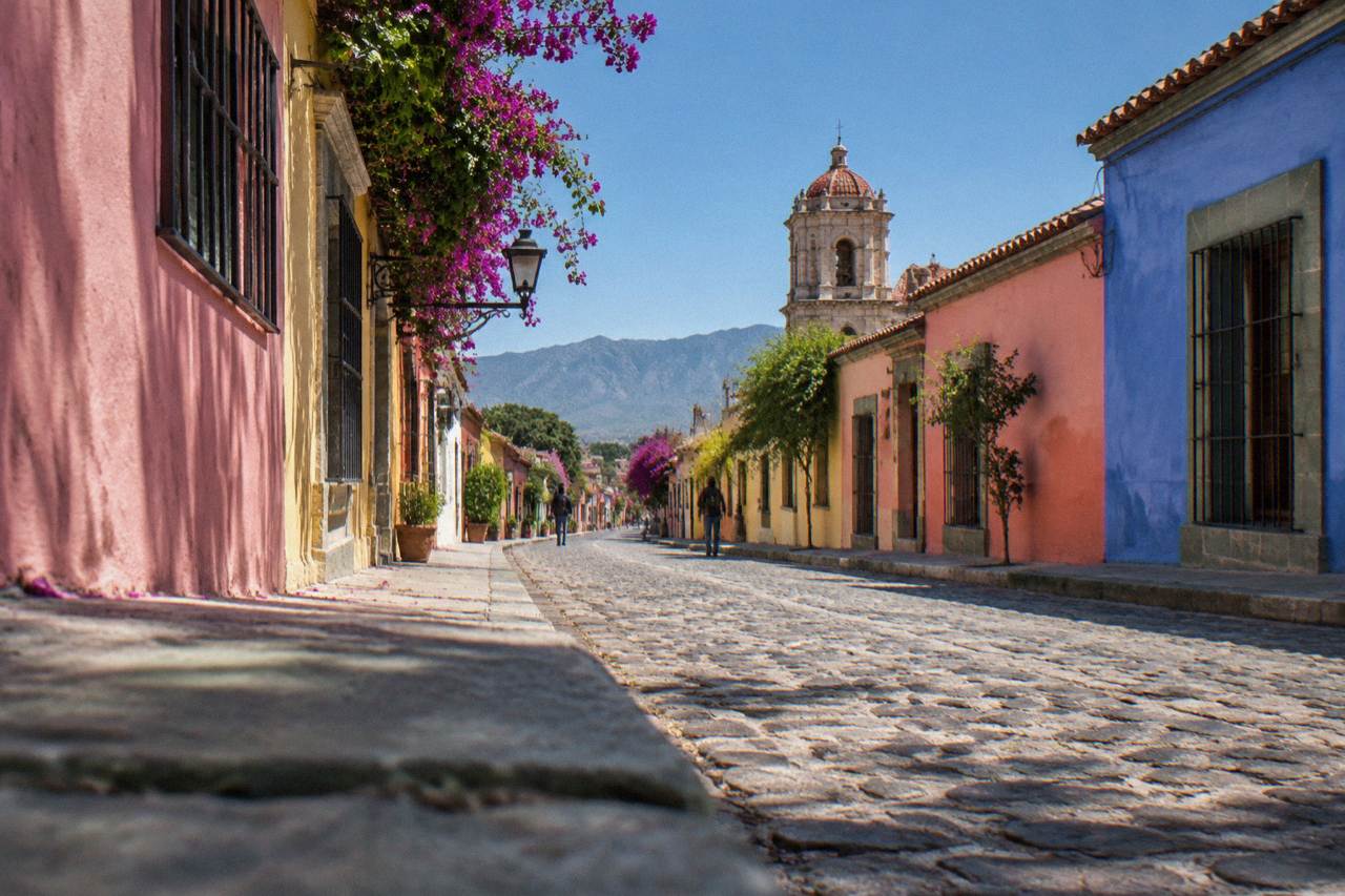 A colourful low-rise street in Oaxaca City with painted facades under afternoon light