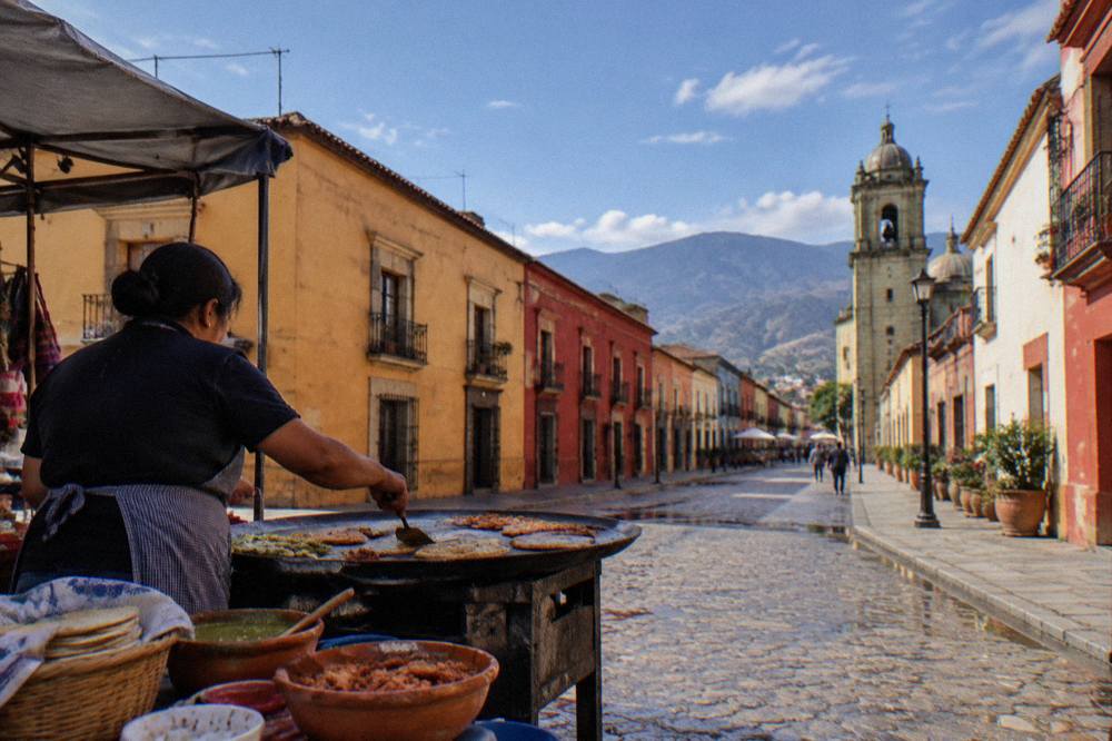 A cook preparing food on a hot griddle at an Oaxacan market stall