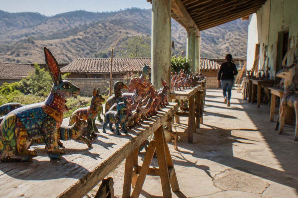 Handcrafted wooden alebrije figures painted in bright patterns on a workshop table