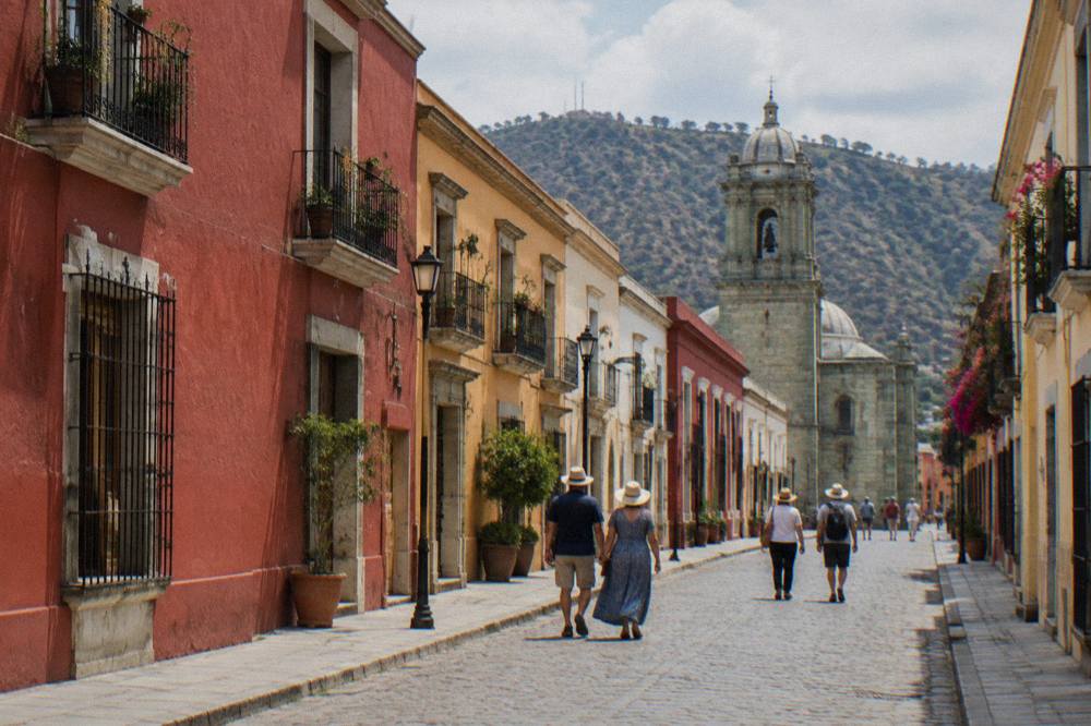 Visitors in sun hats walking on a bright street in central Oaxaca