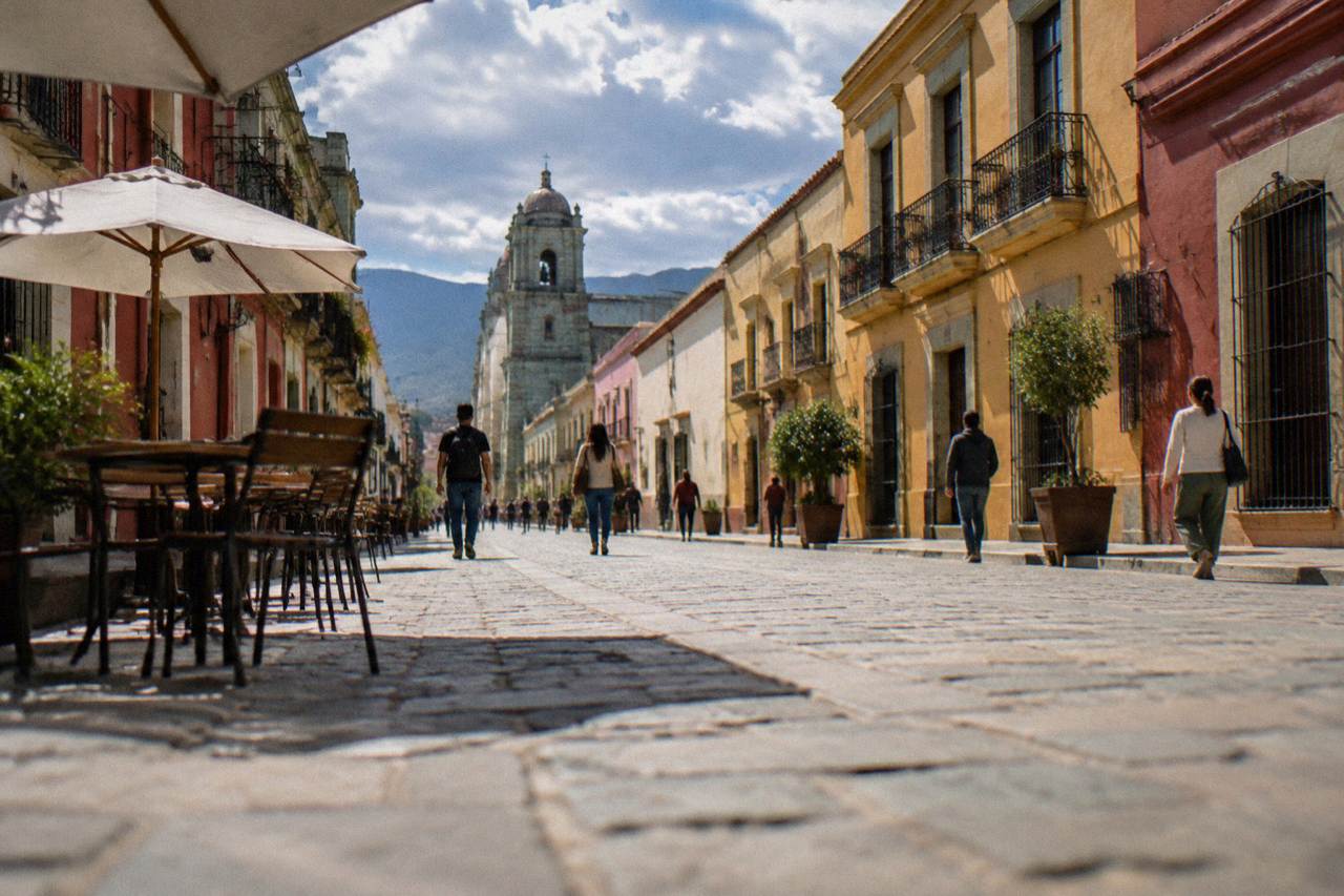 A pedestrian street in Oaxaca City with stone paving, colourful building facades and people walking