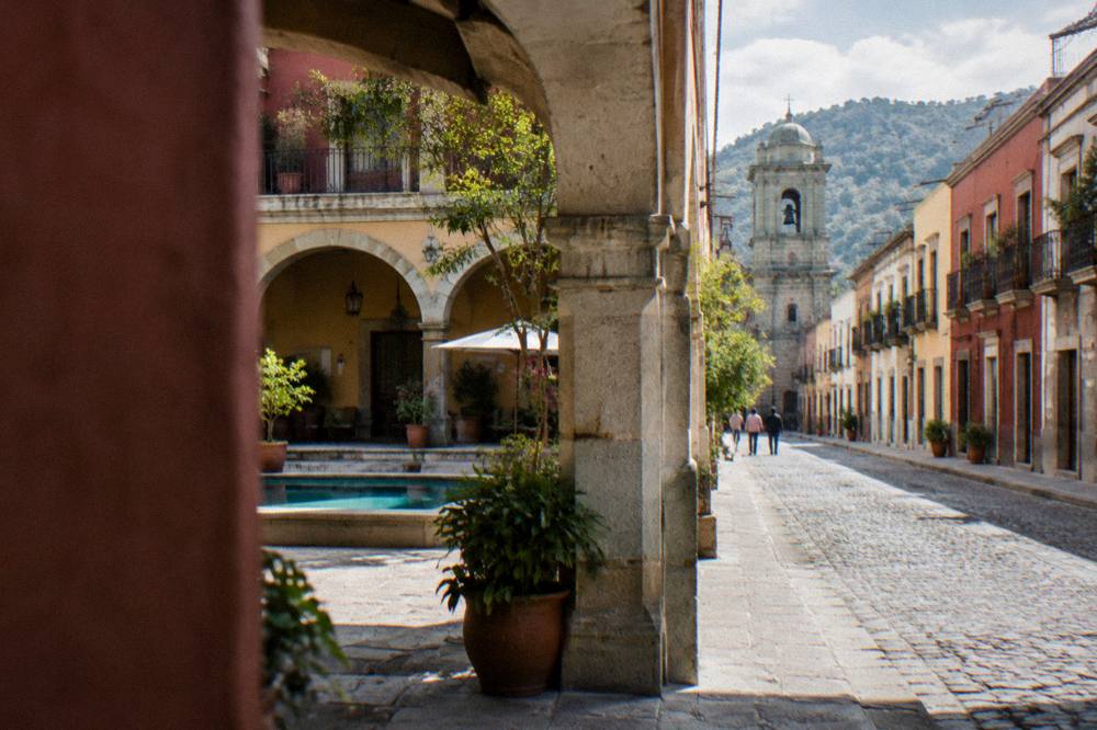 A colonial courtyard hotel with potted plants and stone arches in Oaxaca