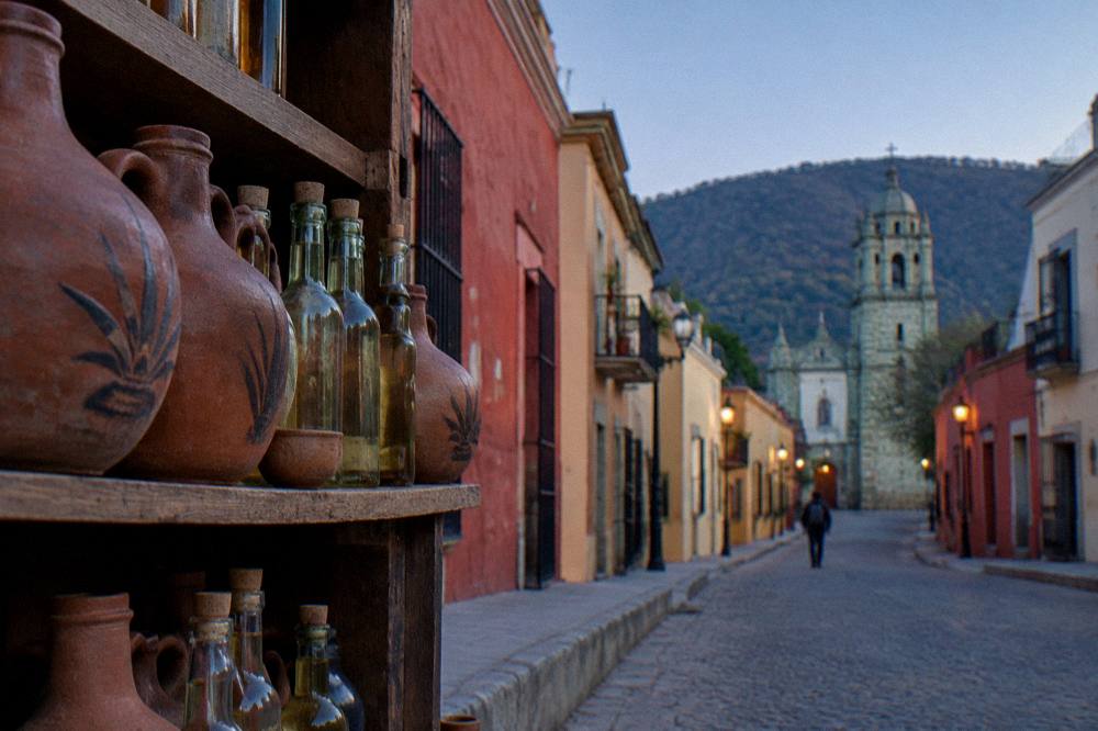 Clay jugs and bottles of mezcal on shelves at a distillery in the Oaxaca valleys