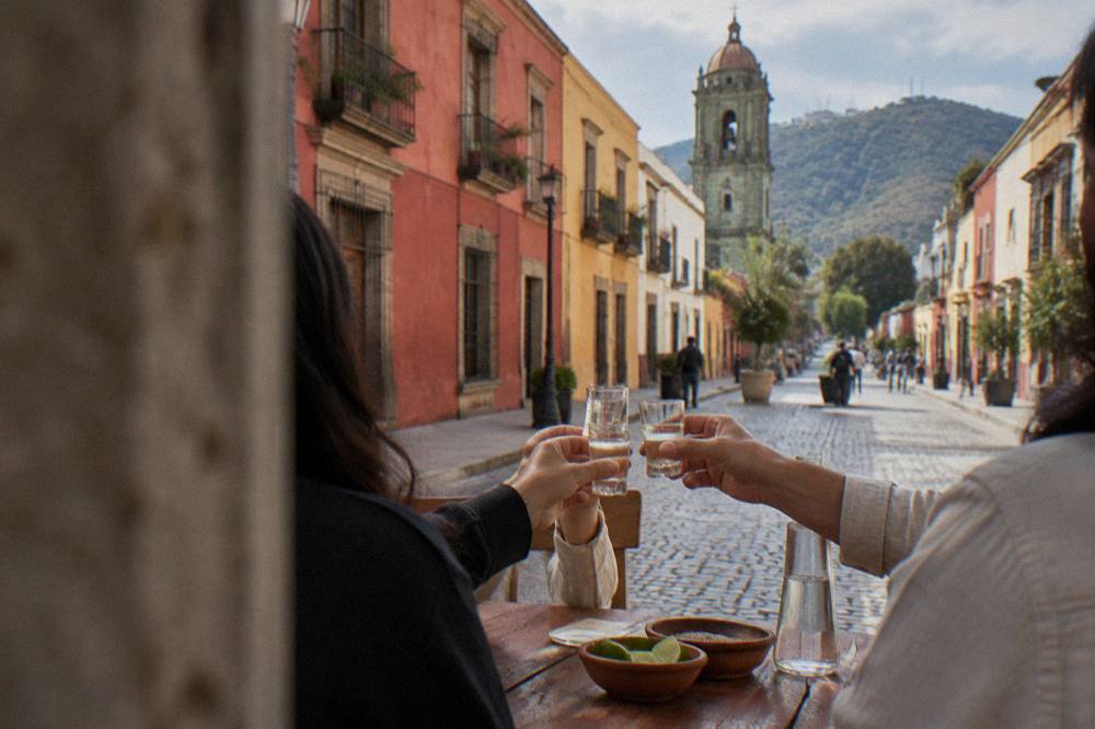 People toasting with small glasses of mezcal at a table in Oaxaca City