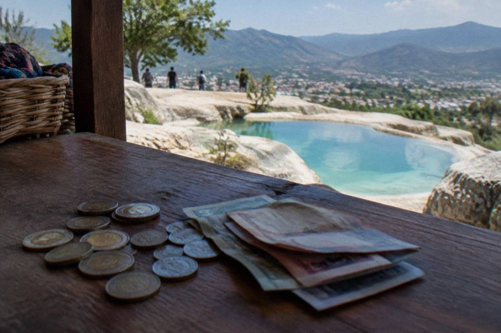 Mexican peso banknotes and coins spread on a wooden market counter