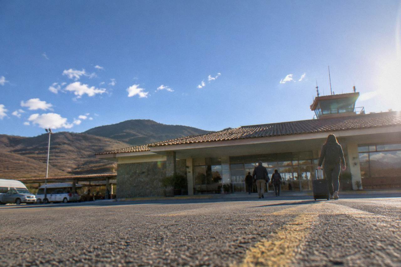 Small airport terminal building under a wide blue sky with hills behind it