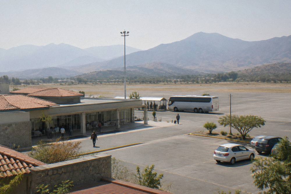Long-distance bus parked at a terminal platform with mountains rising behind it