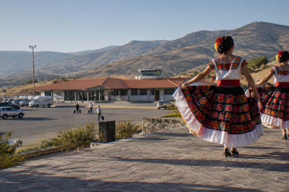 Dancers in traditional embroidered costumes performing on an outdoor hillside stage