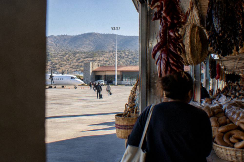 Busy indoor market aisle hung with dried chiles, breads and woven baskets