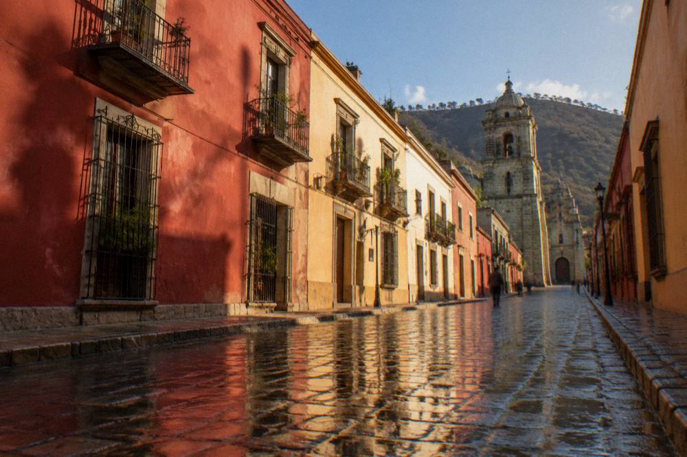 Wet cobblestone street in Oaxaca reflecting colonial building colours after rain