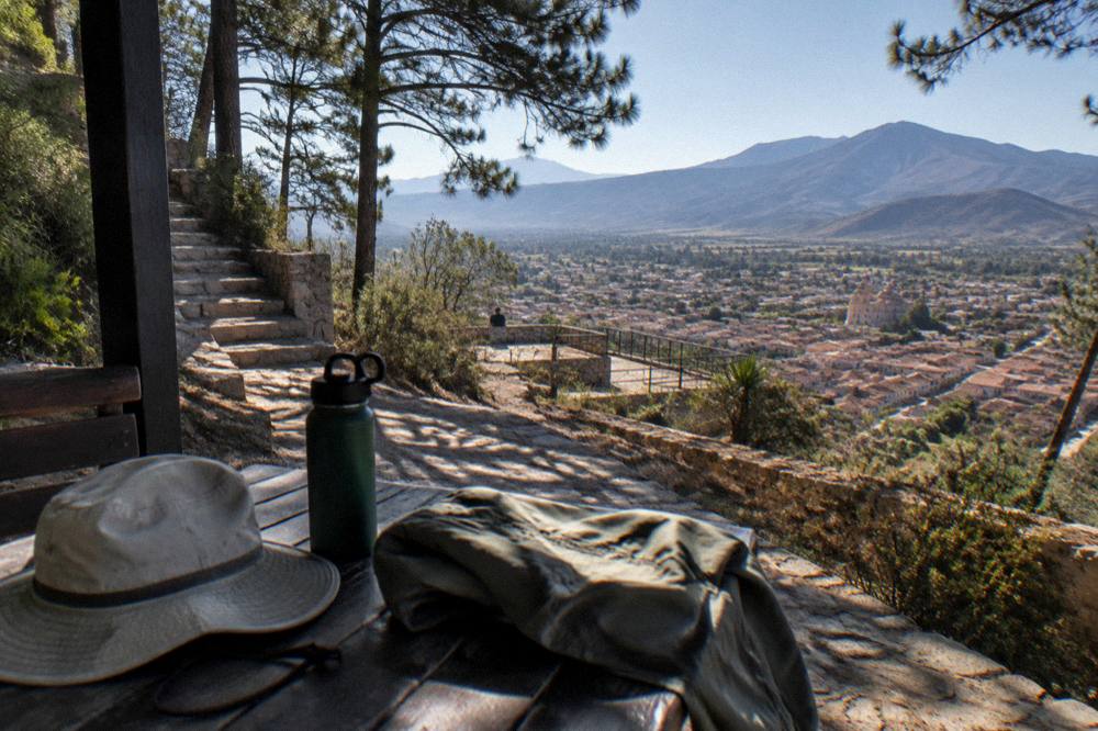 A sun hat, water bottle and light jacket arranged on a table for a highland trip