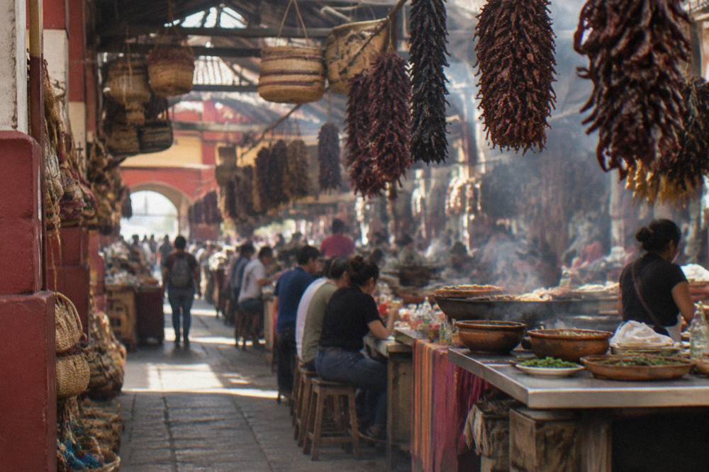 A busy indoor market aisle with vendors and hanging baskets of goods