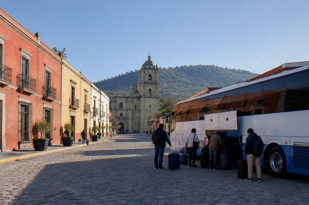 A bus parked at a terminal in Oaxaca with passengers loading luggage