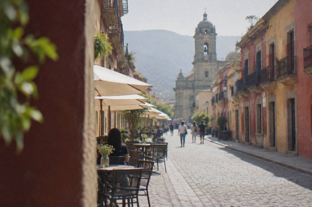 A pedestrian street in Oaxaca's historic centre with colonial facades and café tables