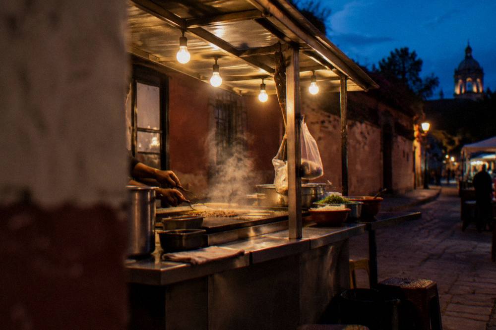 A street food stall at dusk in Oaxaca with steam rising from a griddle