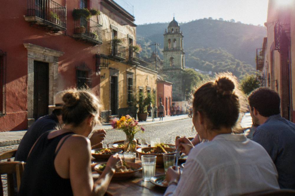 A group of travellers eating together at a wooden table after an Oaxaca cooking class