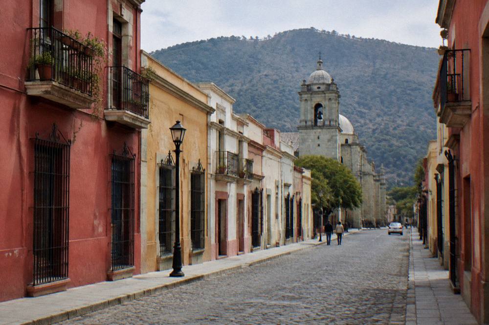 A couple studying a map on a sunlit colonial street in Oaxaca City