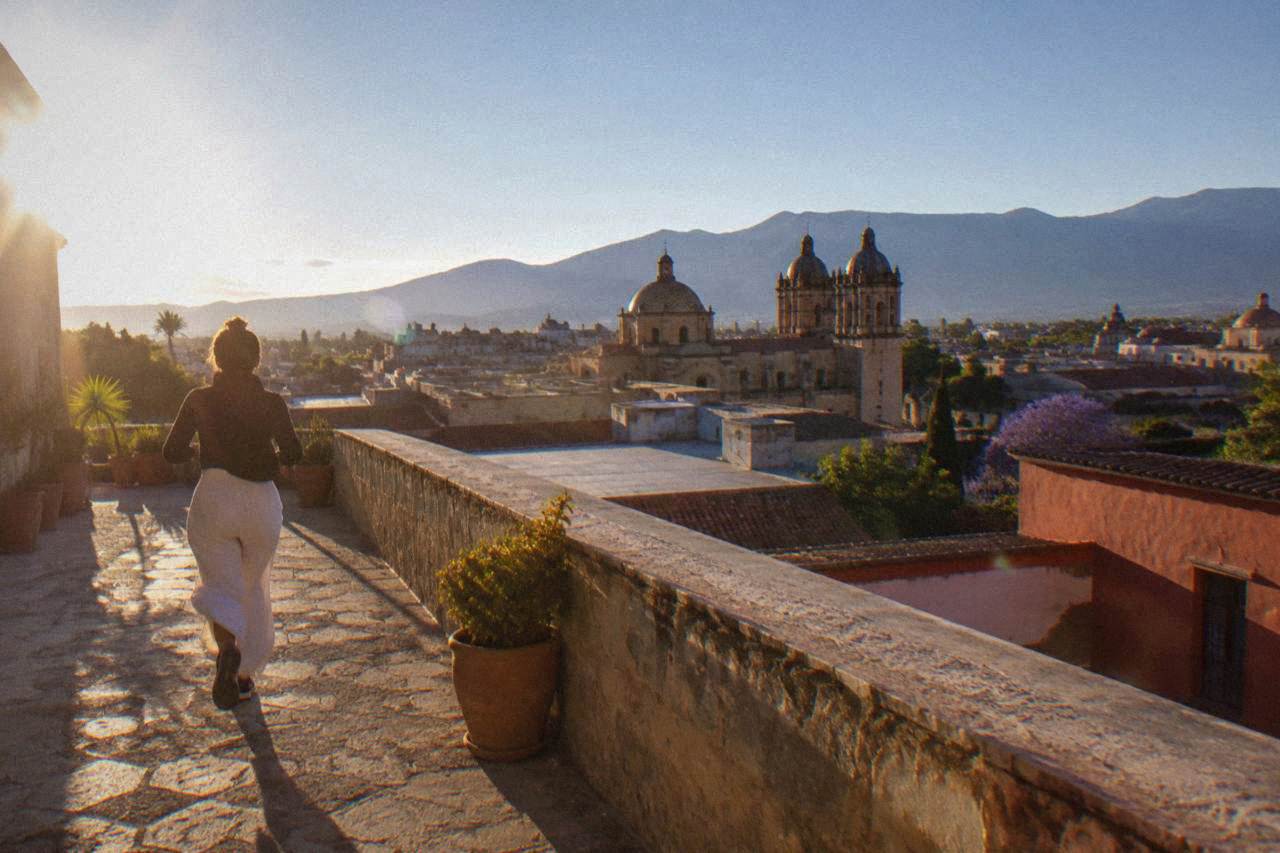 View over the historic centre of Oaxaca City with church domes and tiled rooftops under a blue sky