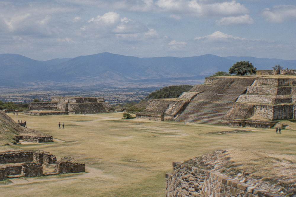 Ancient stone terraces of Monte Albán under a partly cloudy morning sky