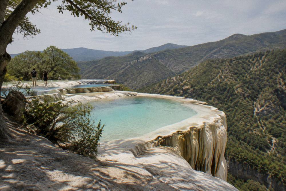 Mineral terraces and pools at Hierve el Agua with green hills behind them