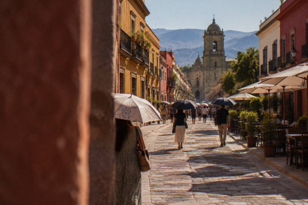 People walking with umbrellas along the Andador Macedonio Alcalá in Oaxaca City