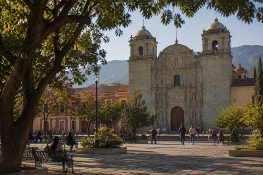 The Zócalo of Oaxaca City with trees, benches and the cathedral on one side