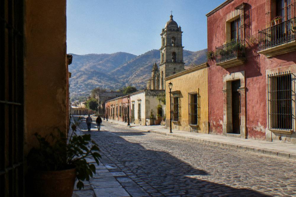 A village street in the Valles Centrales with low coloured buildings and hills behind